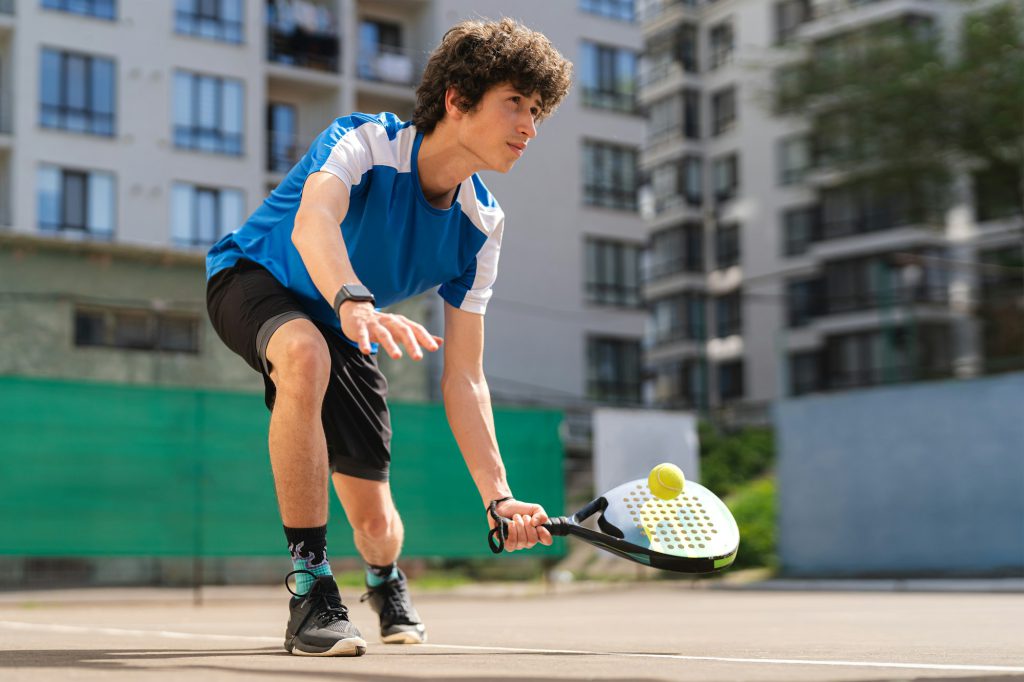 Boy play padel on outdoor tennis court